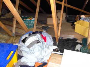 Colour photograph showing the typical clutter which can accumulate, over time, in an Attic Roof Space. Wait and see, however, what else is happening underneath and around this clutter. Smoke Detectors should always be fitted in these Spaces as a matter of routine. Also ... notice that this is a trussed timber roof. Photograph taken by CJ Walsh. 2010-05-21. Click to enlarge.