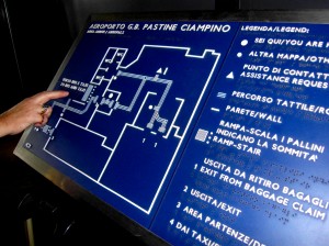 Colour photograph showing a Large Tactile Floor Plan at one of the entrances to the terminal building at Ciampino Airport in Rome, Italy. Notice, in particular, the use of an easily understandable type font combined with the high contrast between white characters and blue background ... the presentation of information in three different languages: Italian, English and Braille ... and, finally, the panel is mounted at a convenient height and angle. Photograph taken by CJ Walsh. 2011-10-26. Click to enlarge.